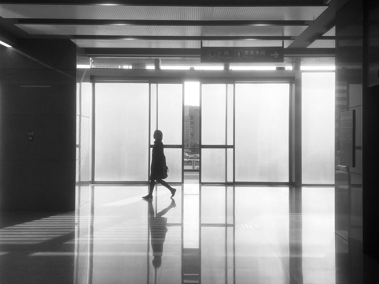 Silhouette walking through a glass station corridor