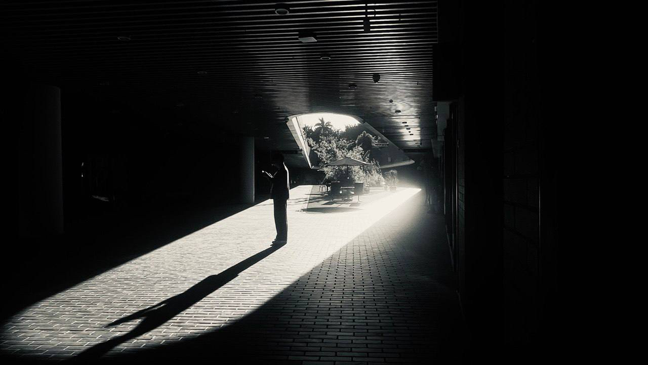 Person standing in a dark underpass with strong light and shadow
